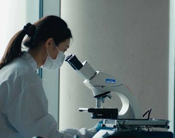 Woman looking down a microscope