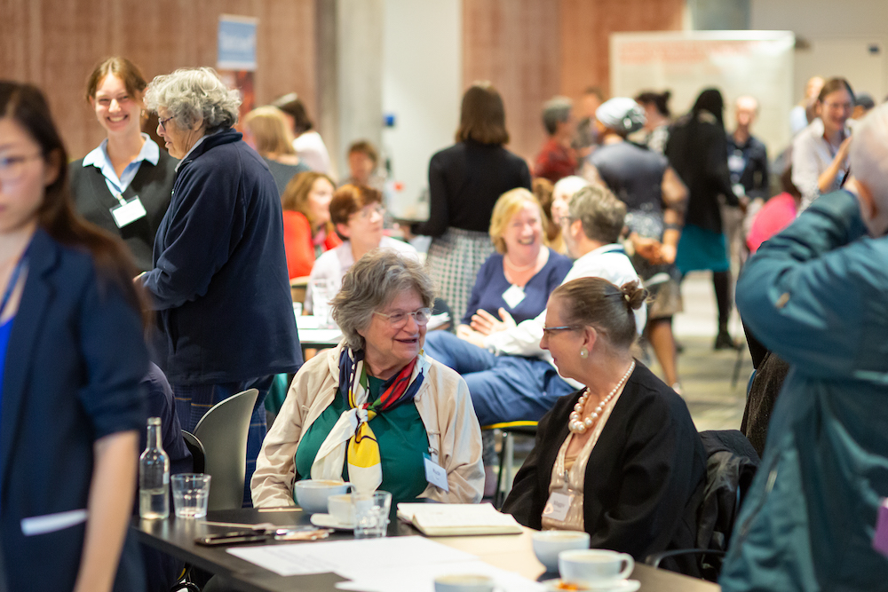 Two older women sit at a table at an event