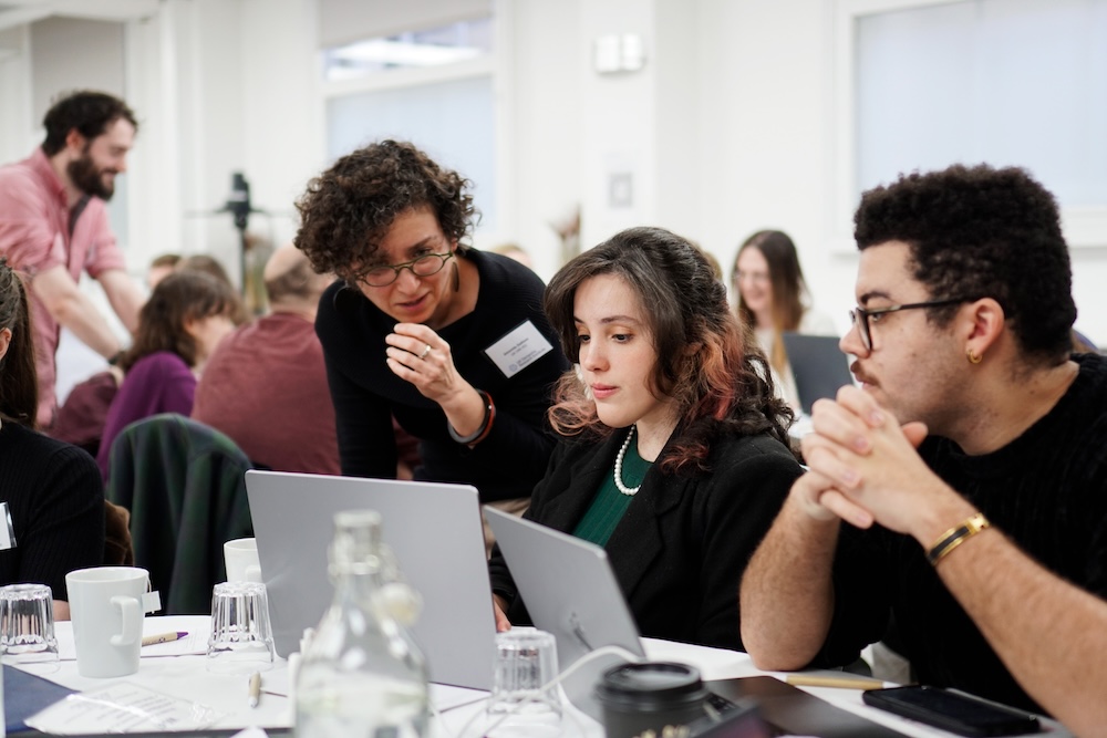 three researchers look at a computer screen at a workshop