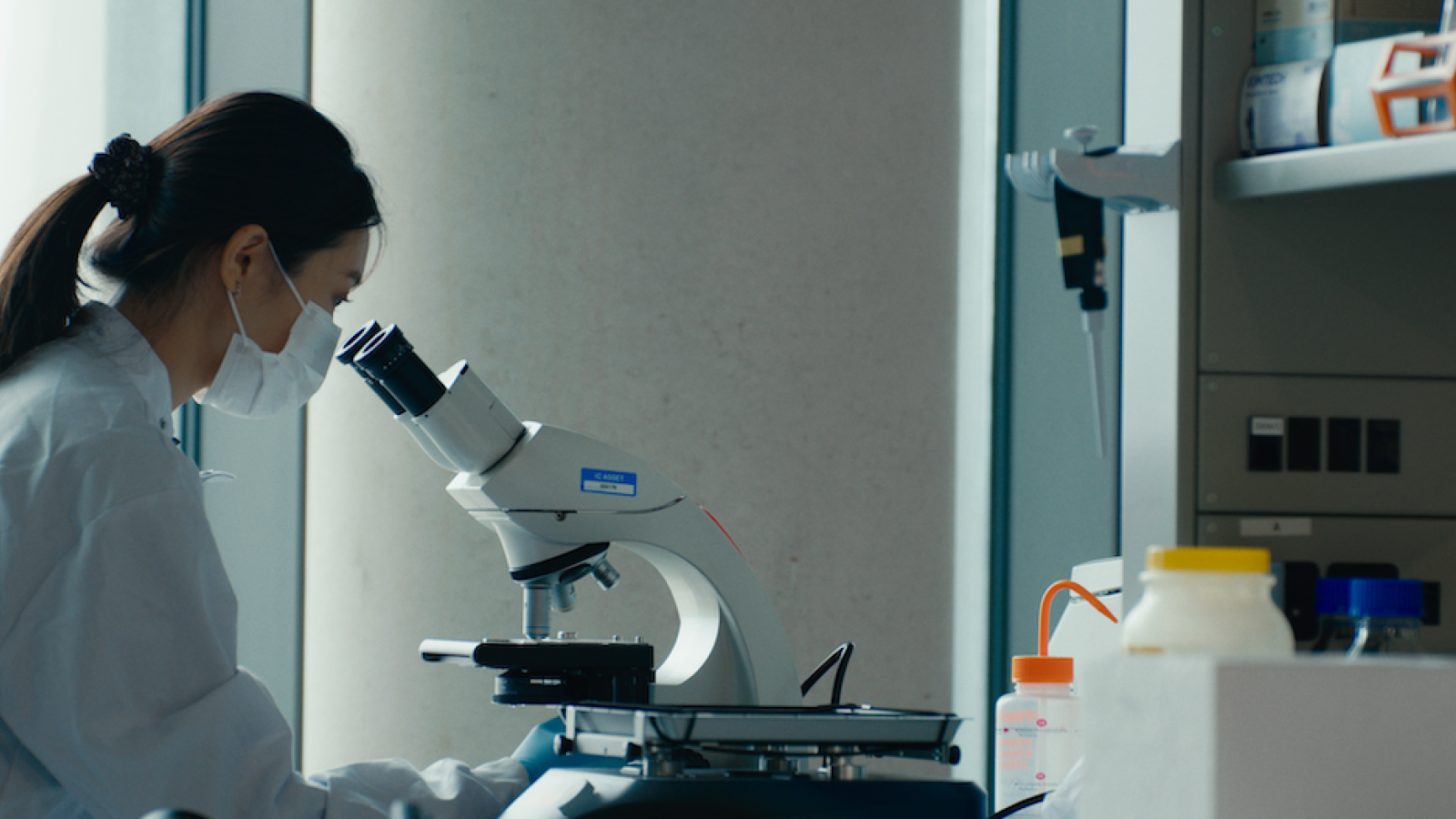 researcher looking down a microscope