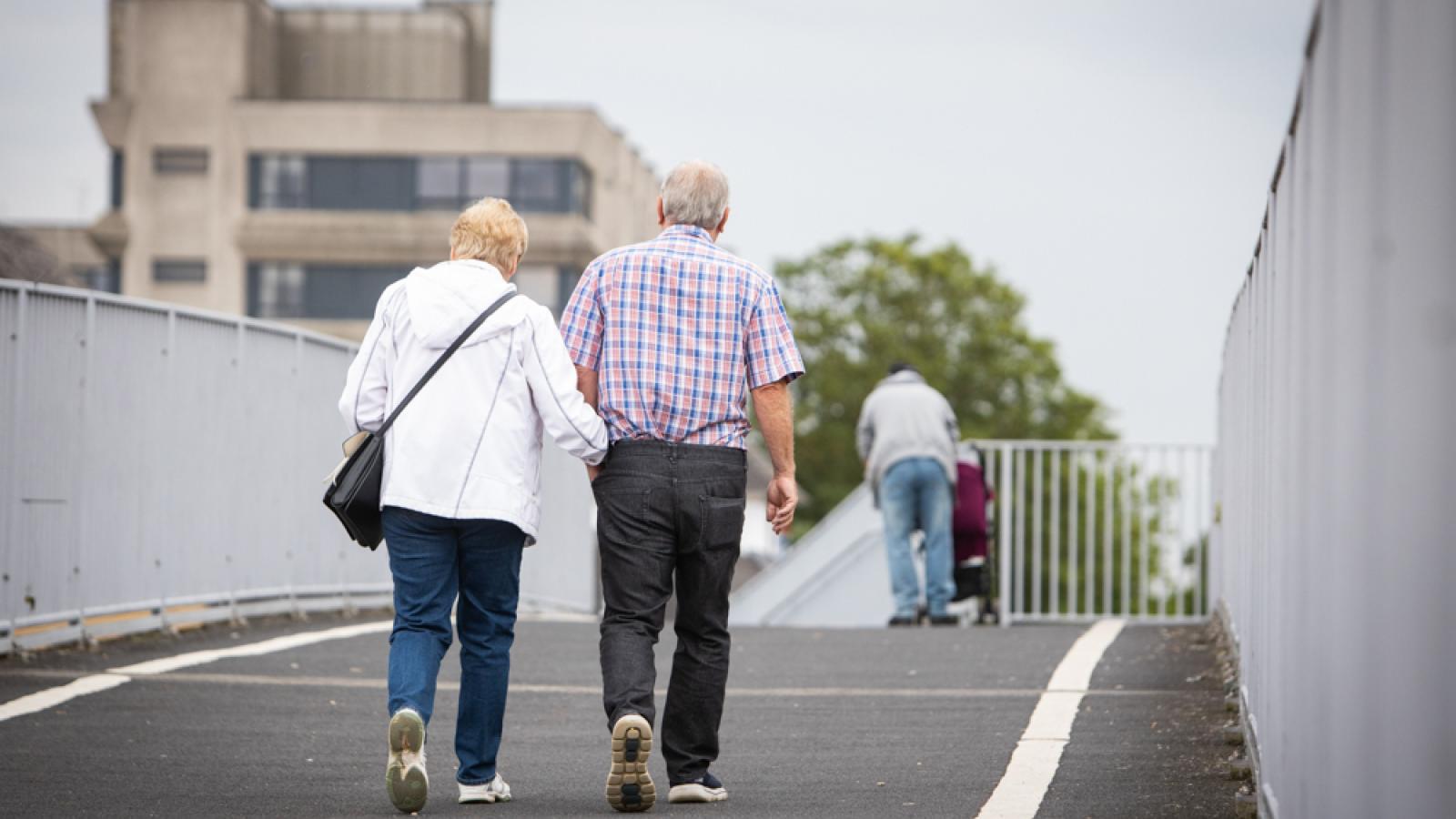 Two people walking across a bridge