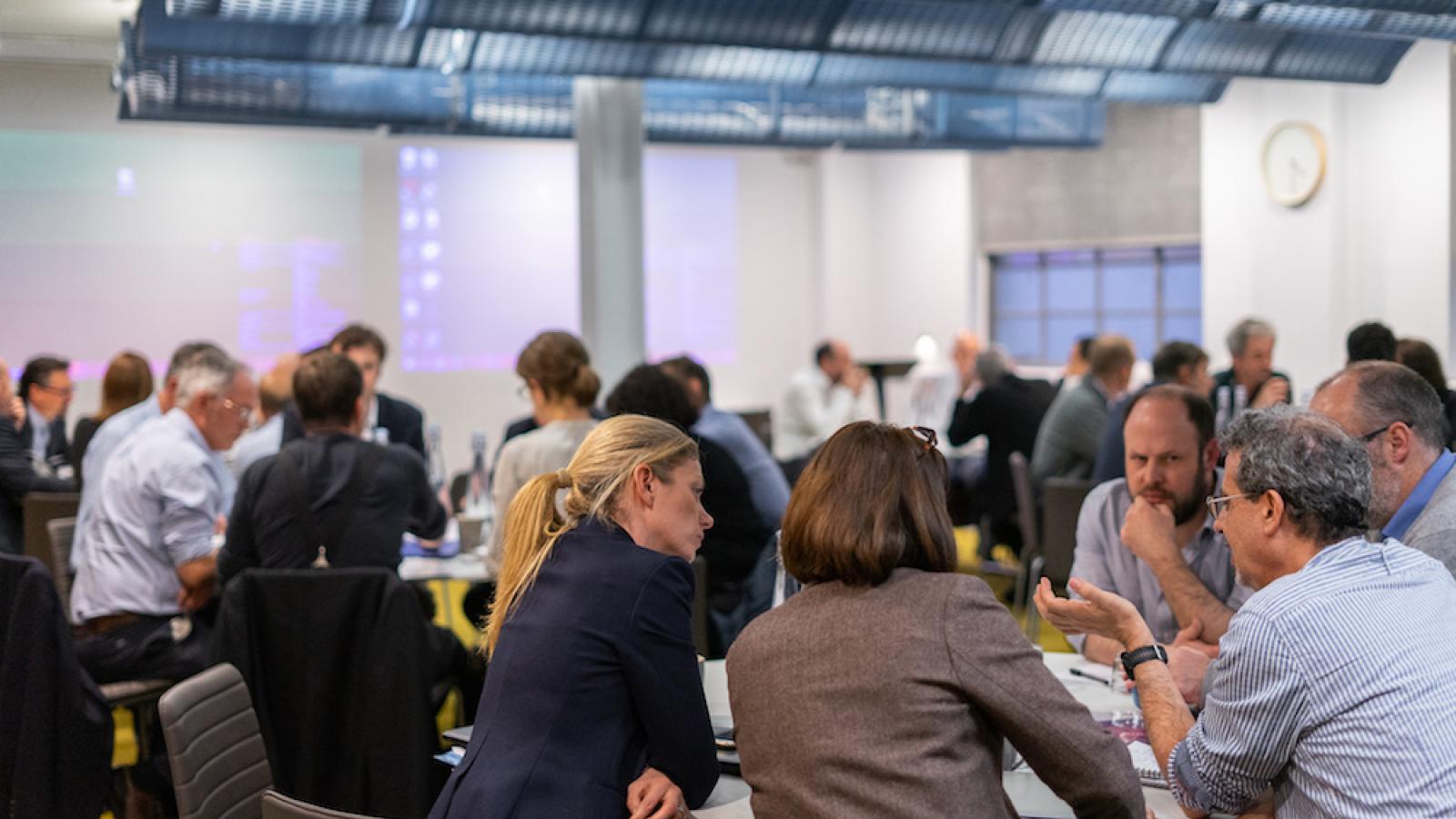A group of people sat chatting on tables in a workshop