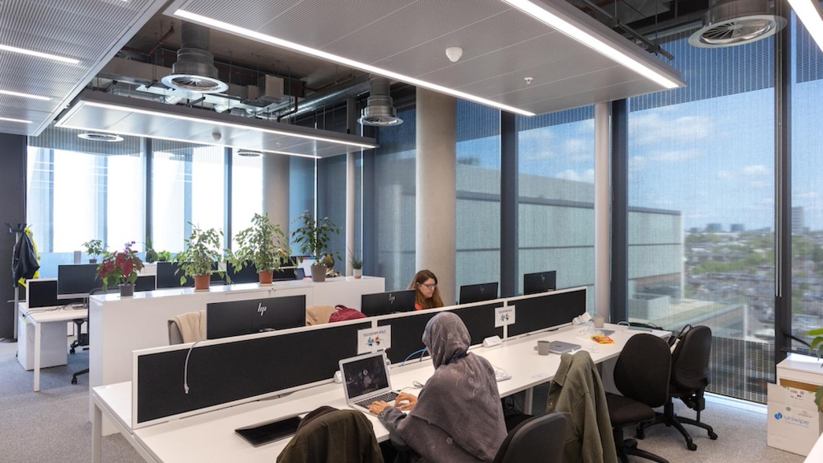 An office space where two people sit on computers