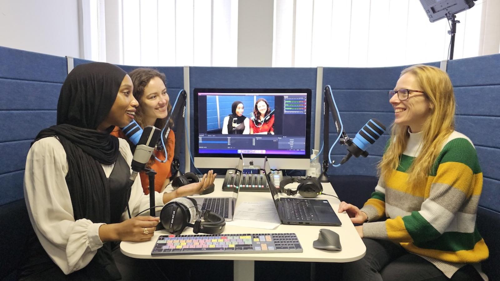 Three researchers in a podcast booth
