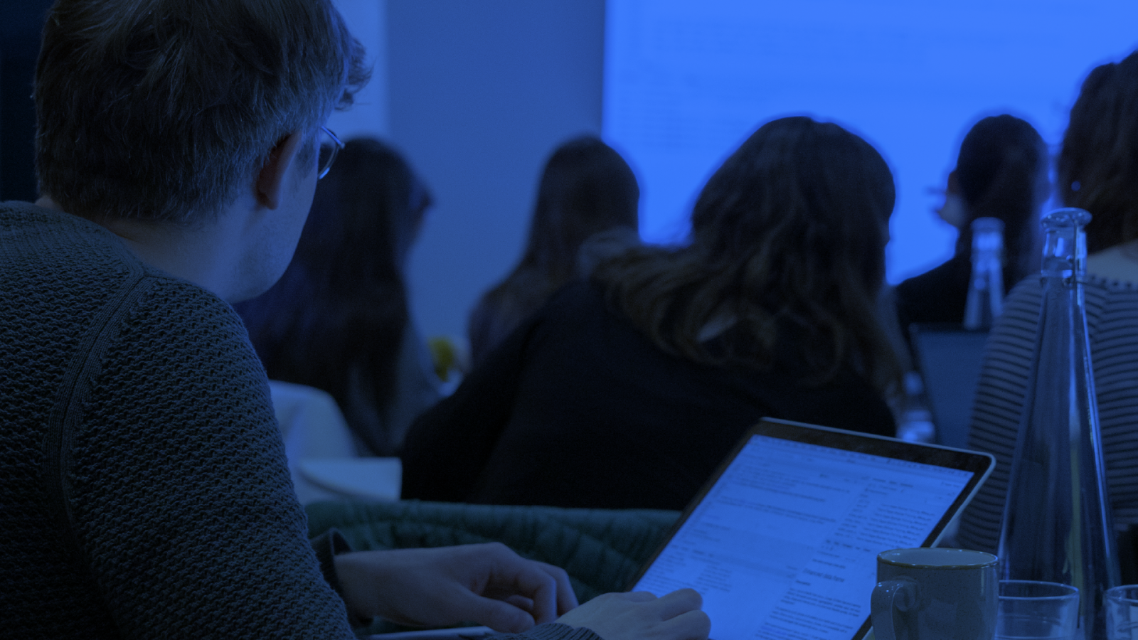 People sit at laptops in a seminar
