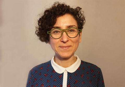 Female with short curly brown hair and glasses