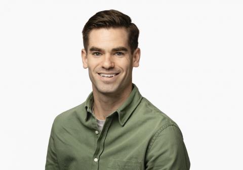 Male with brown hair, smiling, wearing a green shirt