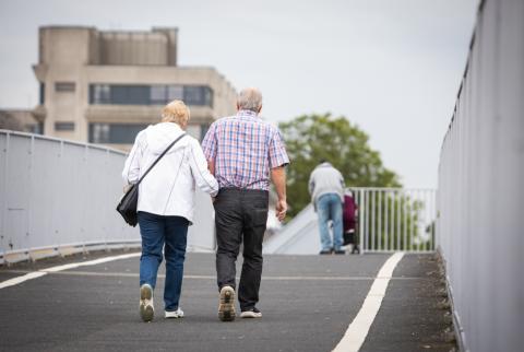 Two people walking across a bridge