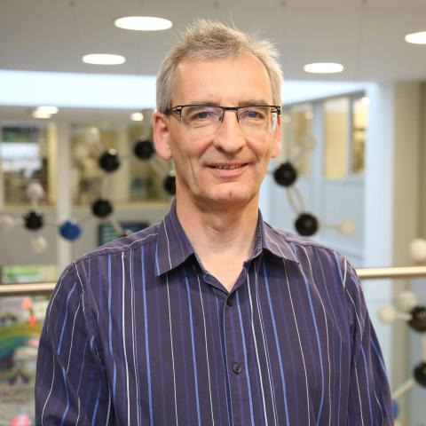 Male with grey hair and rectangular glasses