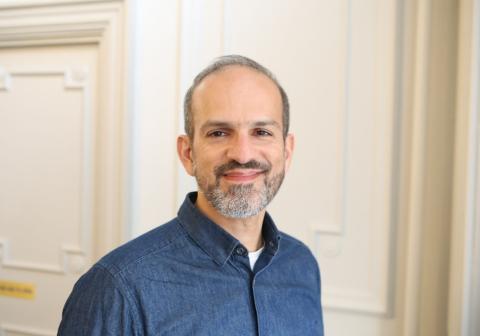 Male with grey hair and a grey beard, wearing a dark blue shirt