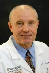 Male wearing a blue shirt under a white lab coat