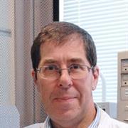 Male with brown/grey hair and wire framed glasses