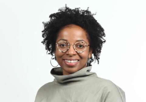 Female with dark brown curly hair and round glasses