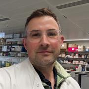 Image of Thomas Cunningham, man with brown hair with glasses in a lab coat