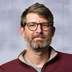 Man with brown hair, brown and grey beard and glasses