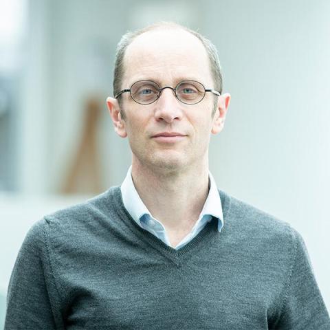 Male with grey hair and round glasses