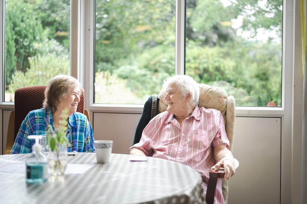 Two older people sitting at a table laughing