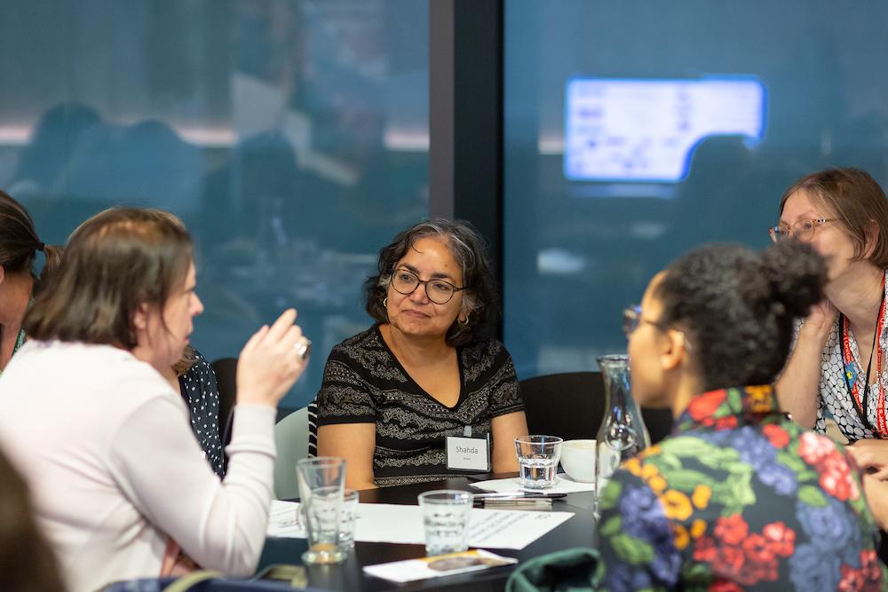 A group of women seated around a table in discussion at an event