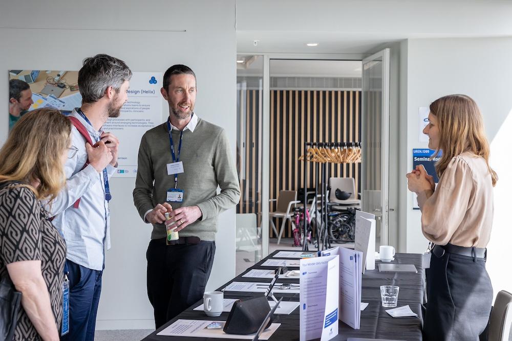 Four people standing and talking near a registration table at an event