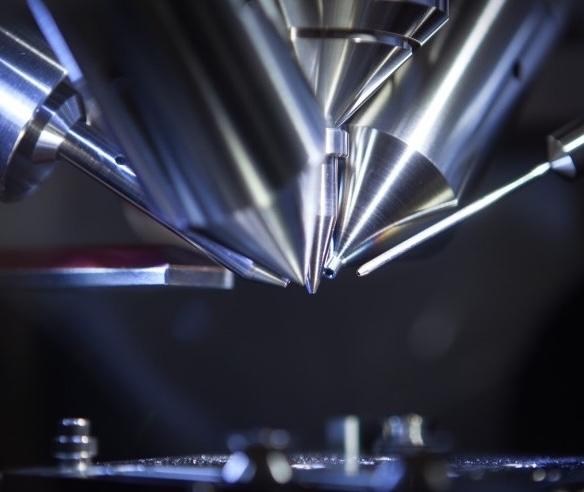 A mass spectrometer Close-up view of shiny metallic probes or needles arranged in a fan-like pattern against a dark background.