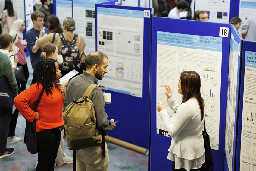 Three individuals in front of academic posters